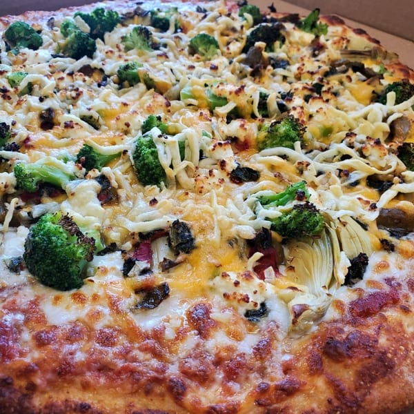 A close-up of a Wasatch Pizza with broccoli, artichoke hearts, mushrooms, and melted cheese.